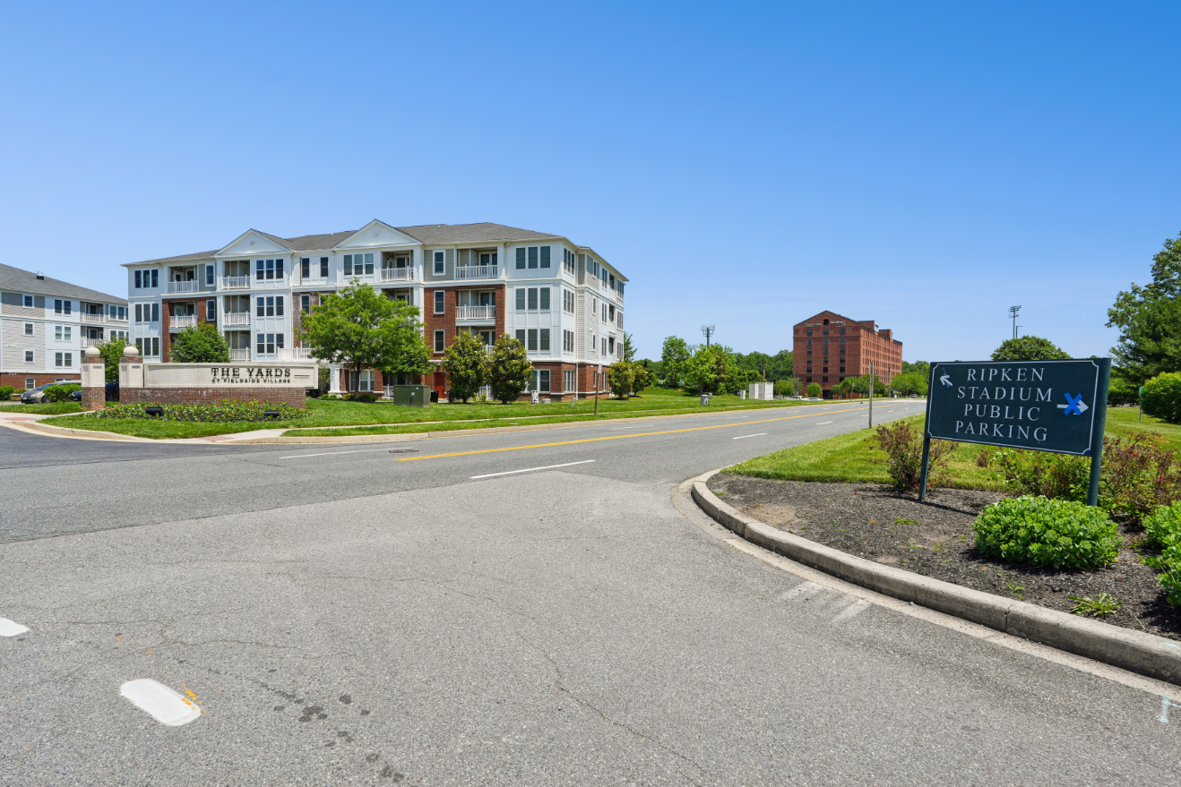 Roadway near The Yards at Fieldside Village with apartment buildings and a Ripken Stadium sign in the distance.