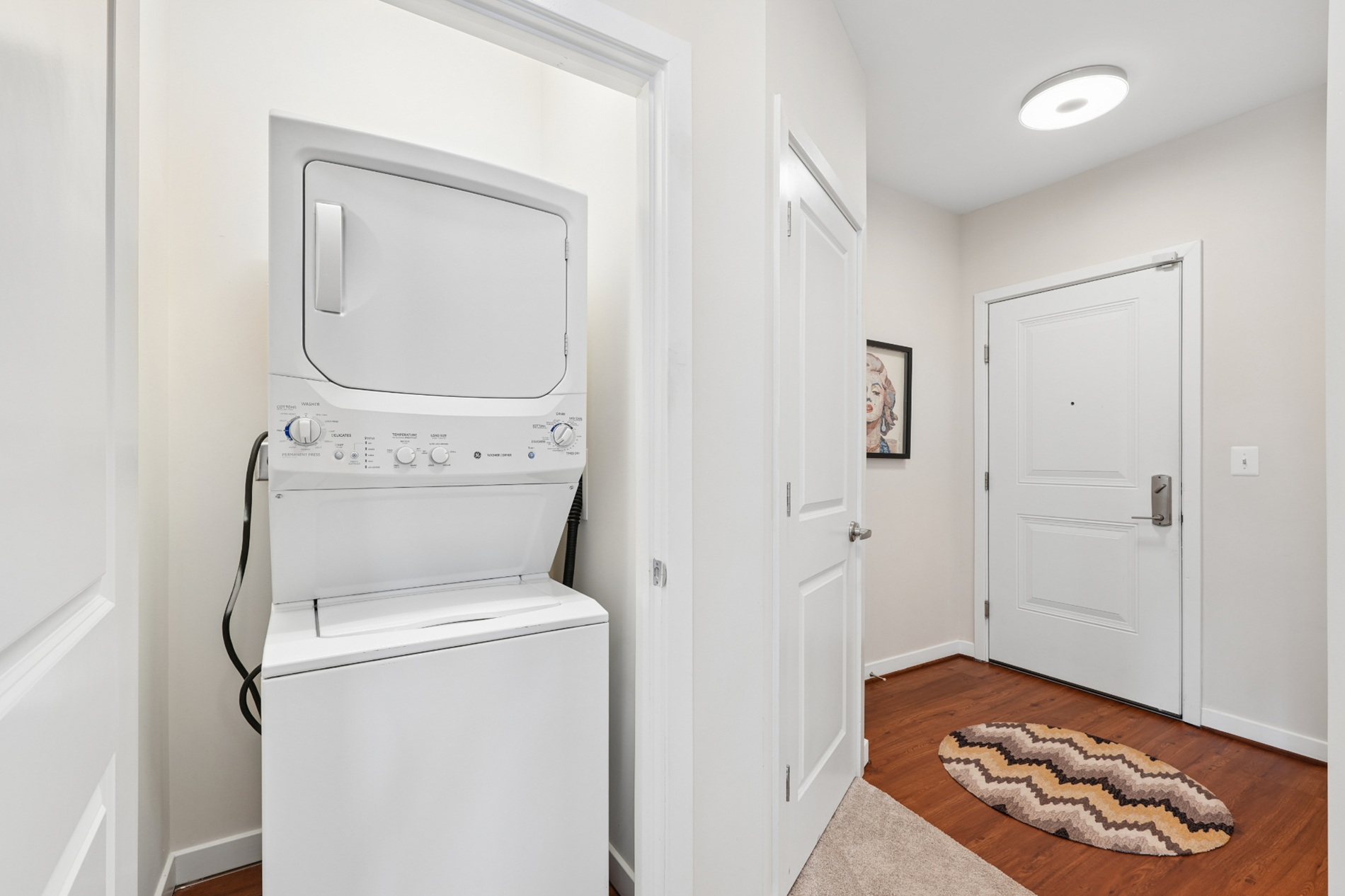 Stacked washer and dryer in an apartment laundry closet near the entry door.