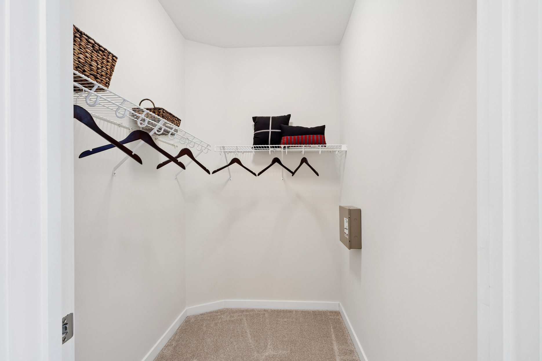 Walk-in closet with white walls, wire shelving, hanging rods, and beige carpet.