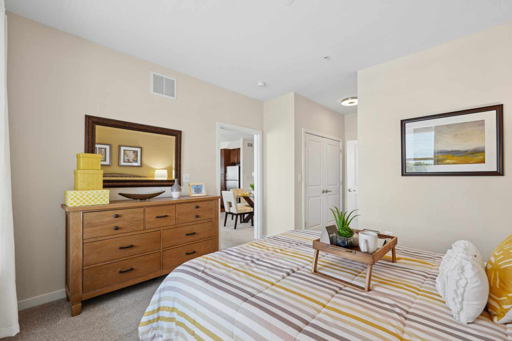 Secondary bedroom with bed, wood dresser, nightstand, window, and view toward the dining area.