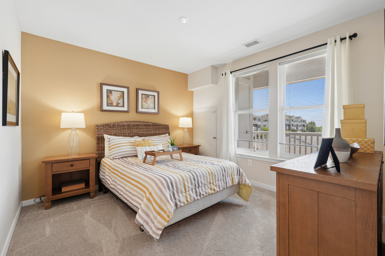 Secondary bedroom with bed, wood nightstands, dresser, two windows, and neutral carpet.